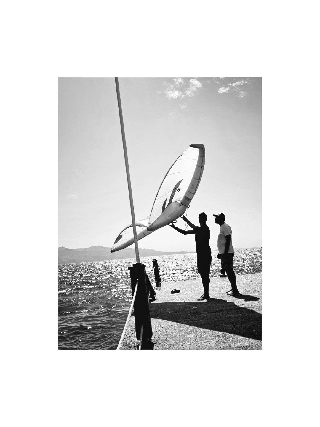 Black and white wing foil coaching moment on the pier at golden hour